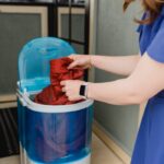 Woman using a compact portable washing machine in a cozy mobile home setting.